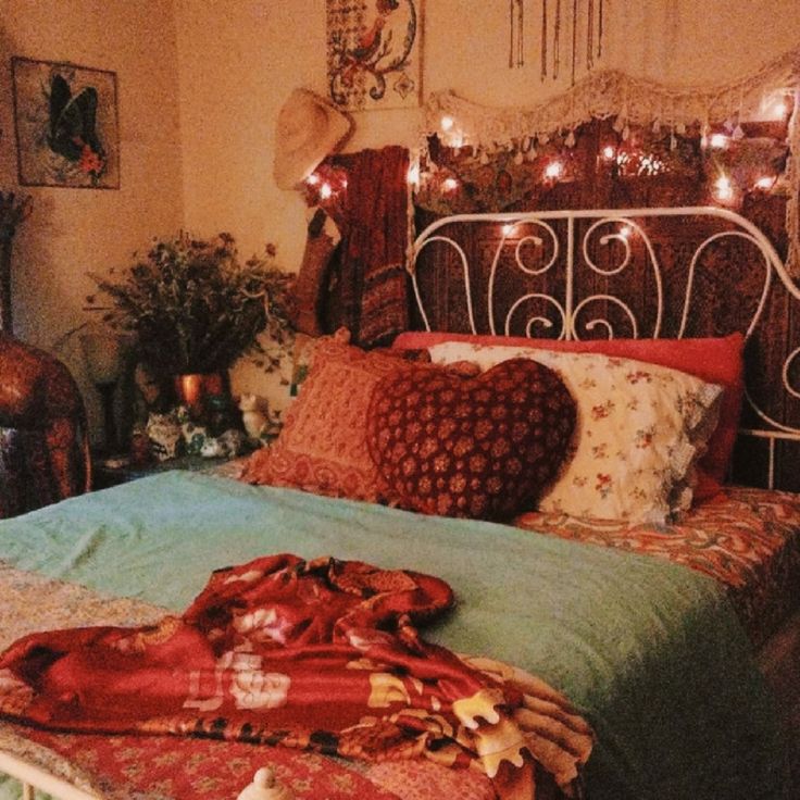 a bed with lots of pillows and blankets on it's headboard in a bedroom