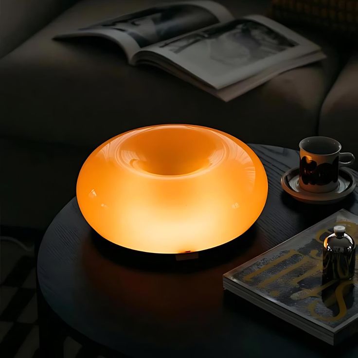 a table with a lamp on top of it next to a book and coffee cup