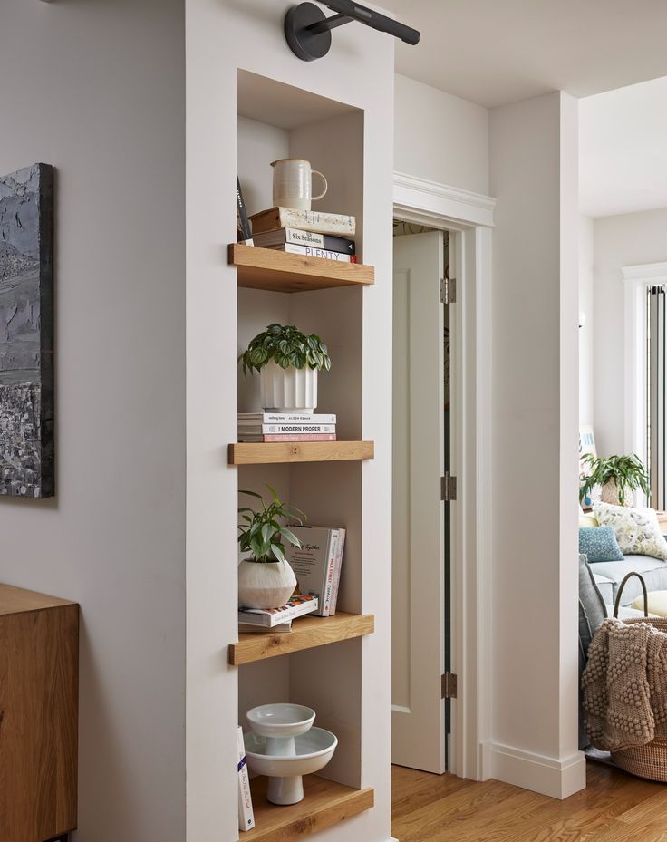 a living room filled with furniture and a book shelf next to a doorway that leads to a bedroom