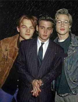 three young men standing next to each other in front of a rain soaked background with one man wearing a suit and tie