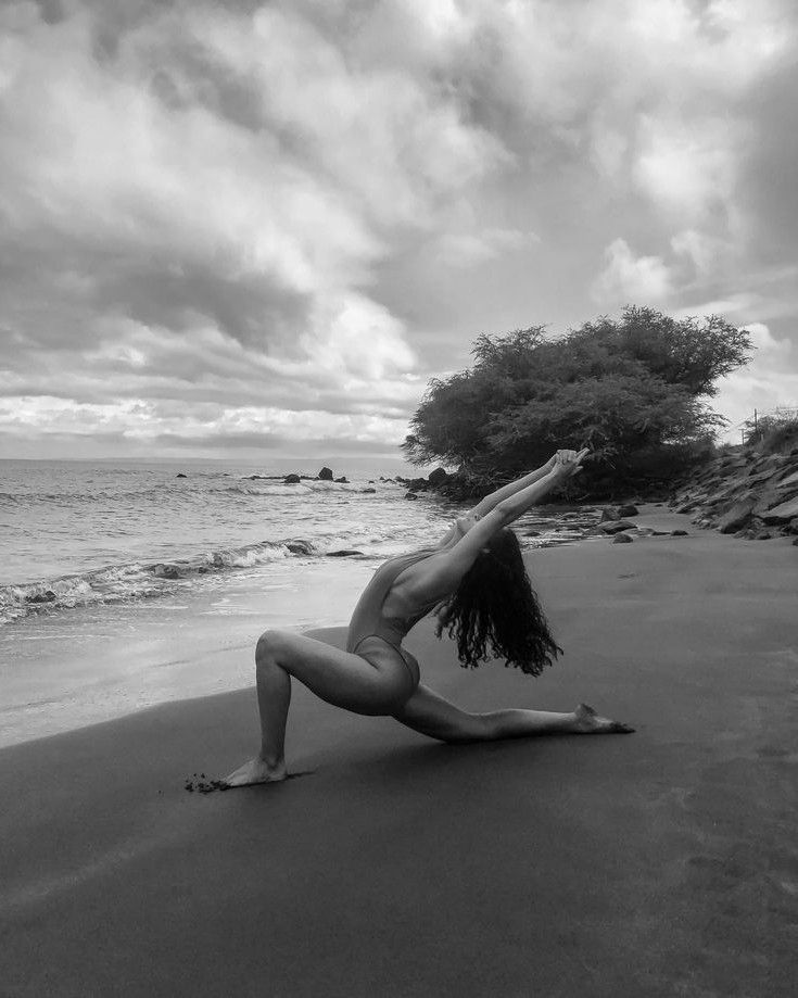 a woman is doing yoga on the beach