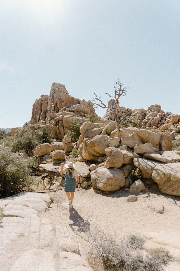 a woman is walking through the desert with large rocks