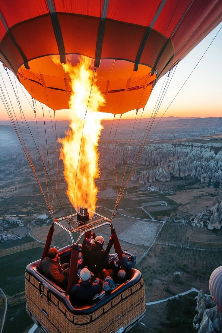 people in a hot air balloon with fire coming out of the basket and into the sky