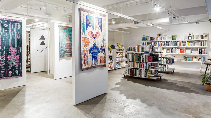 an art gallery with bookshelves and paintings on the walls