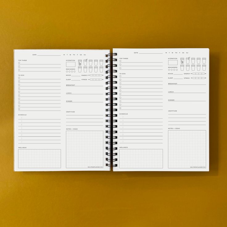 a spiral bound planner is open on a yellow surface