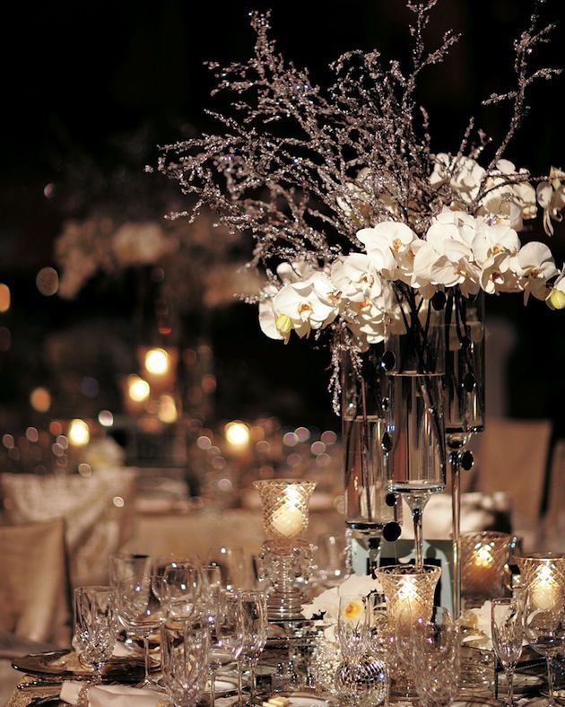 a vase filled with white flowers sitting on top of a table covered in lots of candles