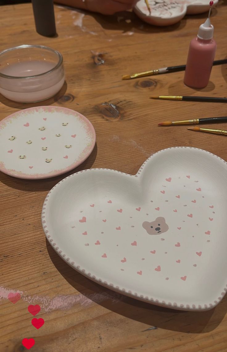 two heart shaped plates sitting on top of a wooden table next to other crafting supplies