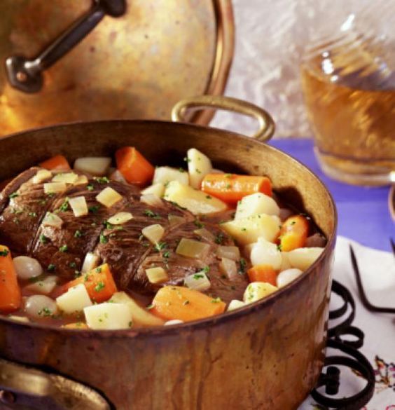 a pot filled with meat and vegetables on top of a table next to other dishes