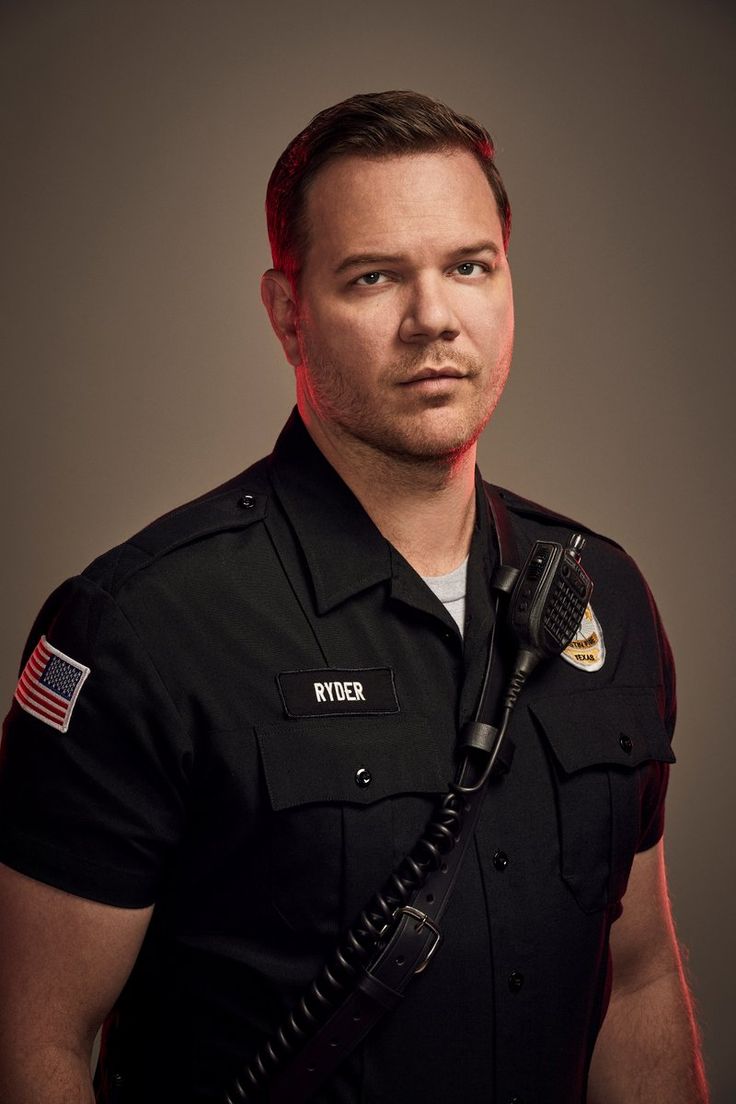 a man in uniform is posing for a photo with a microphone on his shoulder and an american flag on his chest