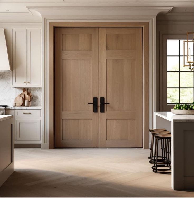 an open kitchen with two wooden doors and stools next to the counter top,