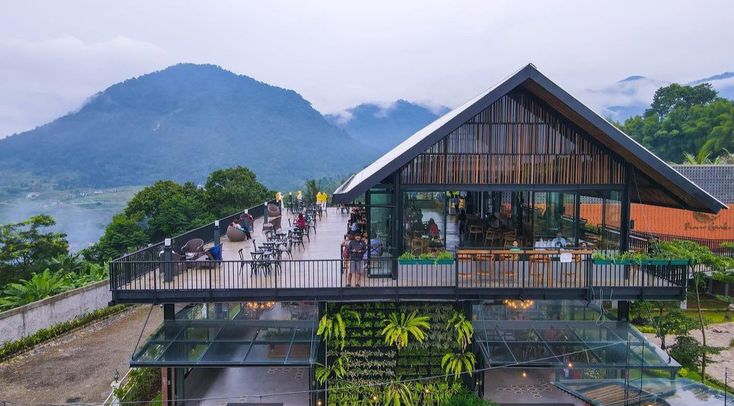 people are walking up and down an elevated walkway in front of a building with plants growing on it