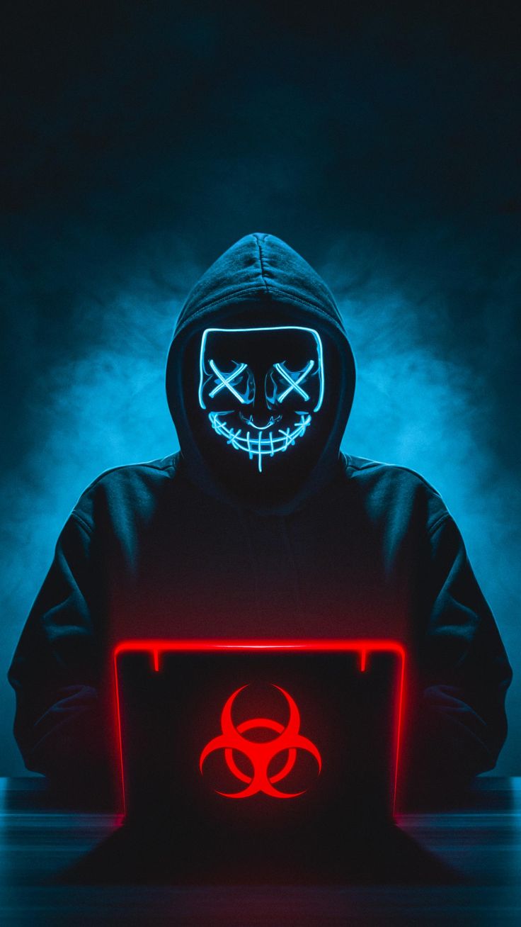 a person in a hoodie with a glowing laptop