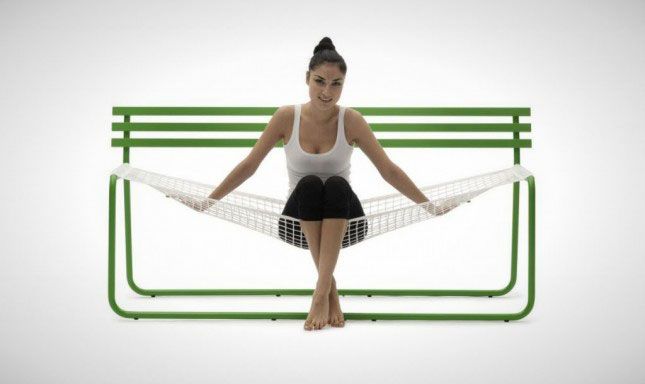 a woman is sitting on a hammock in front of a white wall and green frame