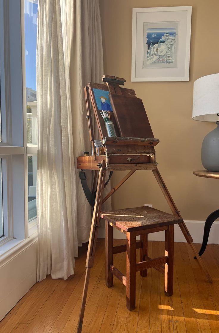 an easel sitting on top of a wooden table next to a window