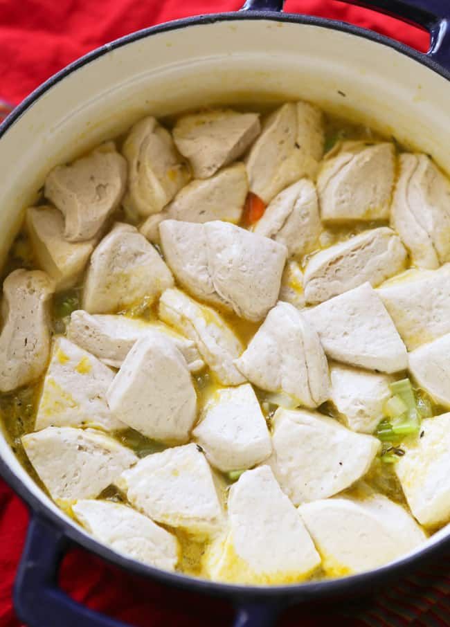 a pot filled with chicken and broth on top of a red cloth