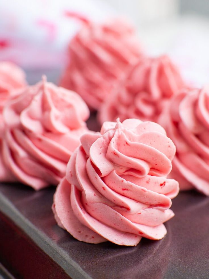 pink frosted cupcakes sitting on top of a table