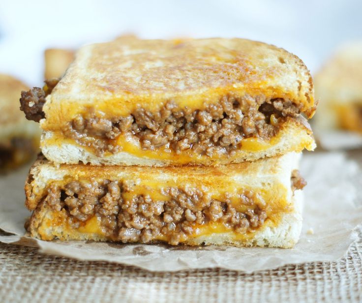 two grilled cheeseburger sandwiches stacked on top of each other with meat toppings