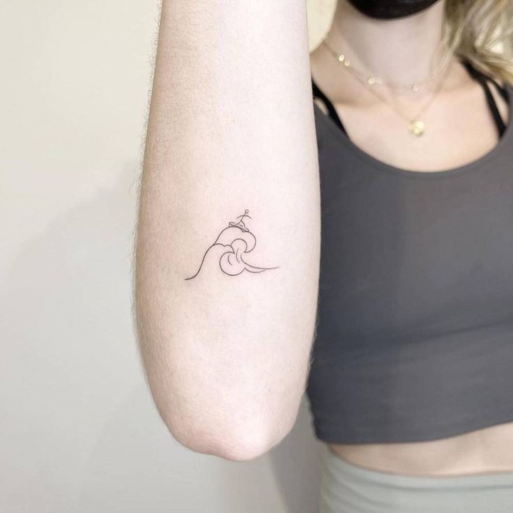 a woman's arm with a small wave tattoo on the left side of her arm