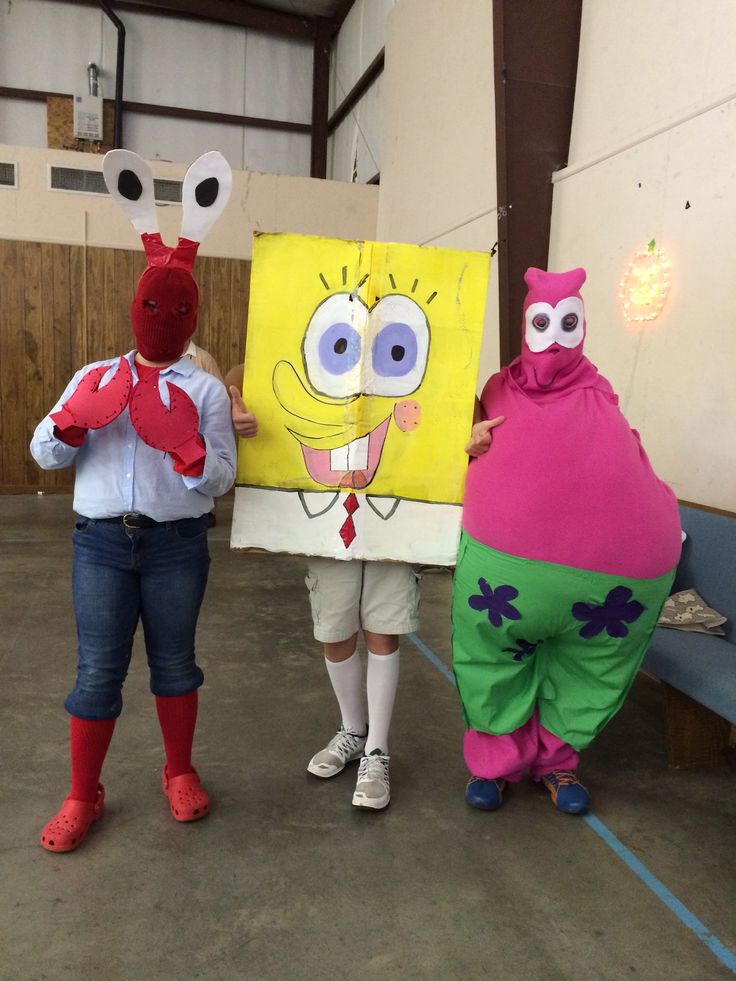 three people in costumes standing next to each other holding up an art piece that looks like spongebob