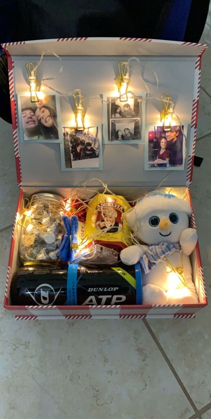 an open box filled with pictures and lights on top of a tile floor next to a teddy bear