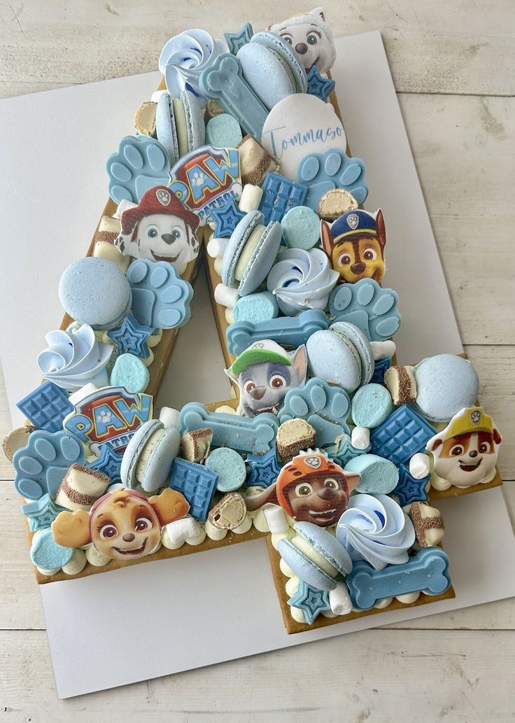 a letter made out of cookies on top of a white paper with teddy bears and other items