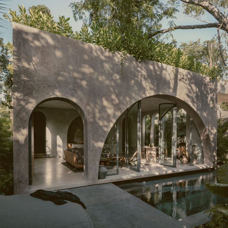 the house is surrounded by trees and has an outdoor swimming pool in front of it