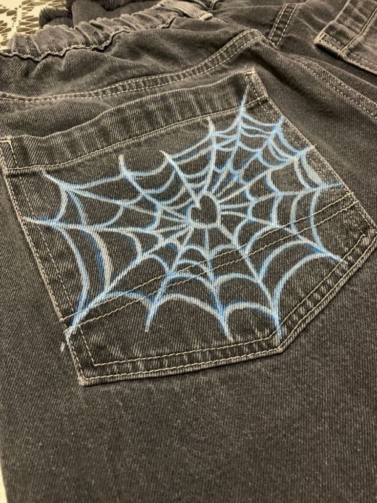 a spider web is drawn on the back pocket of a pair of jean pants that are worn by someone