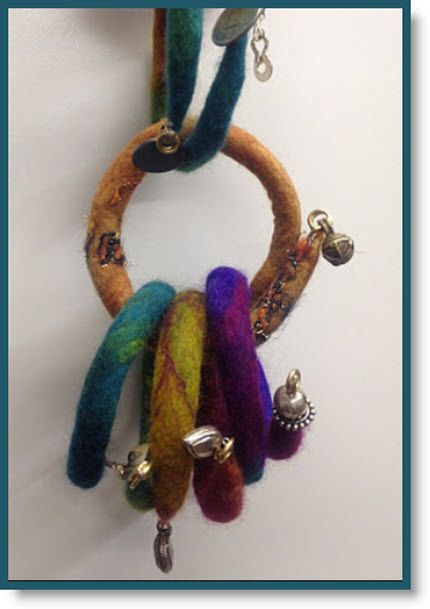 a multicolored necklace with bells hanging from it's side on a white wall