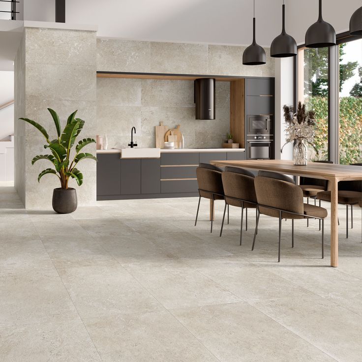 a modern kitchen and dining room with concrete flooring, large windows, potted plant on the counter