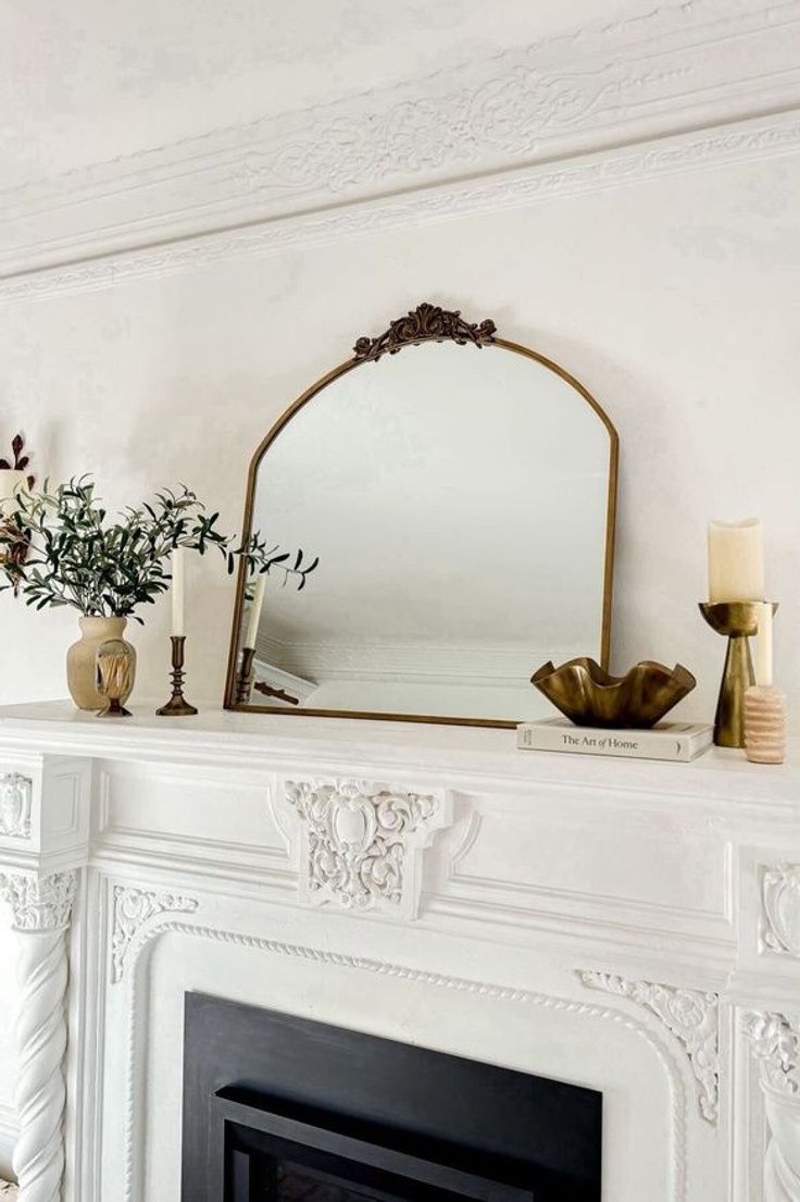 a white fireplace with a mirror and vases on it's mantel above the fire place