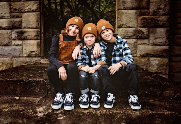 three children sitting on steps wearing hats and overalls with their arms around each other