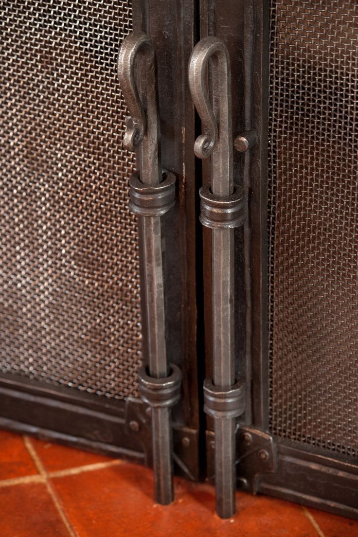 two metal doors with handles on each side and an iron mesh screen behind the door