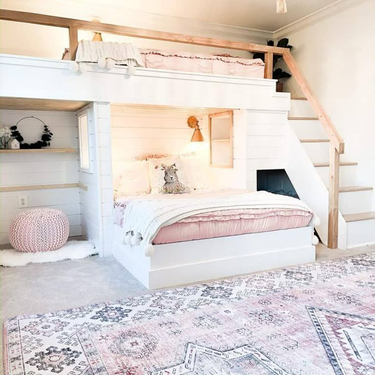 a white bed sitting under a wooden staircase next to a pink rug on top of a floor