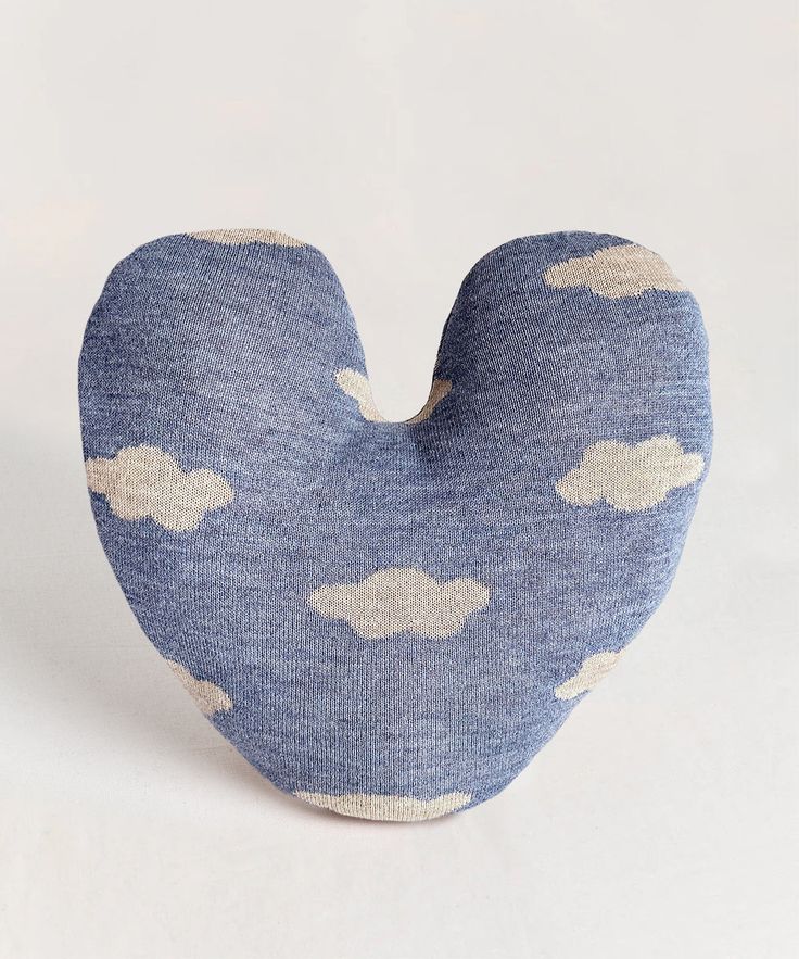 a blue and white heart shaped pillow with clouds printed on the front, sitting against a white background