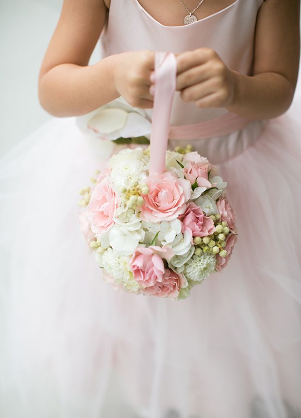 a woman in a pink dress is holding a bouquet with white and pink flowers on it