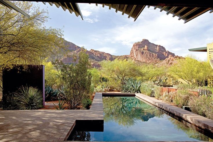 an outdoor swimming pool surrounded by trees and mountains in the background with water running through it