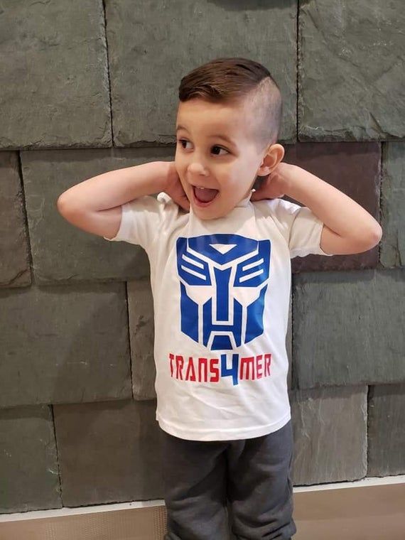 a little boy standing in front of a brick wall with his hands on his head