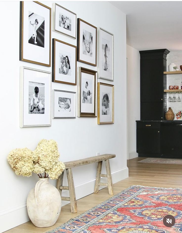 a living room with pictures on the wall and a bench in front of an area rug