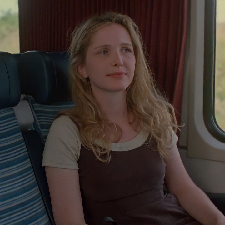 a woman is sitting on a train looking out the window and waiting for someone to take her seat