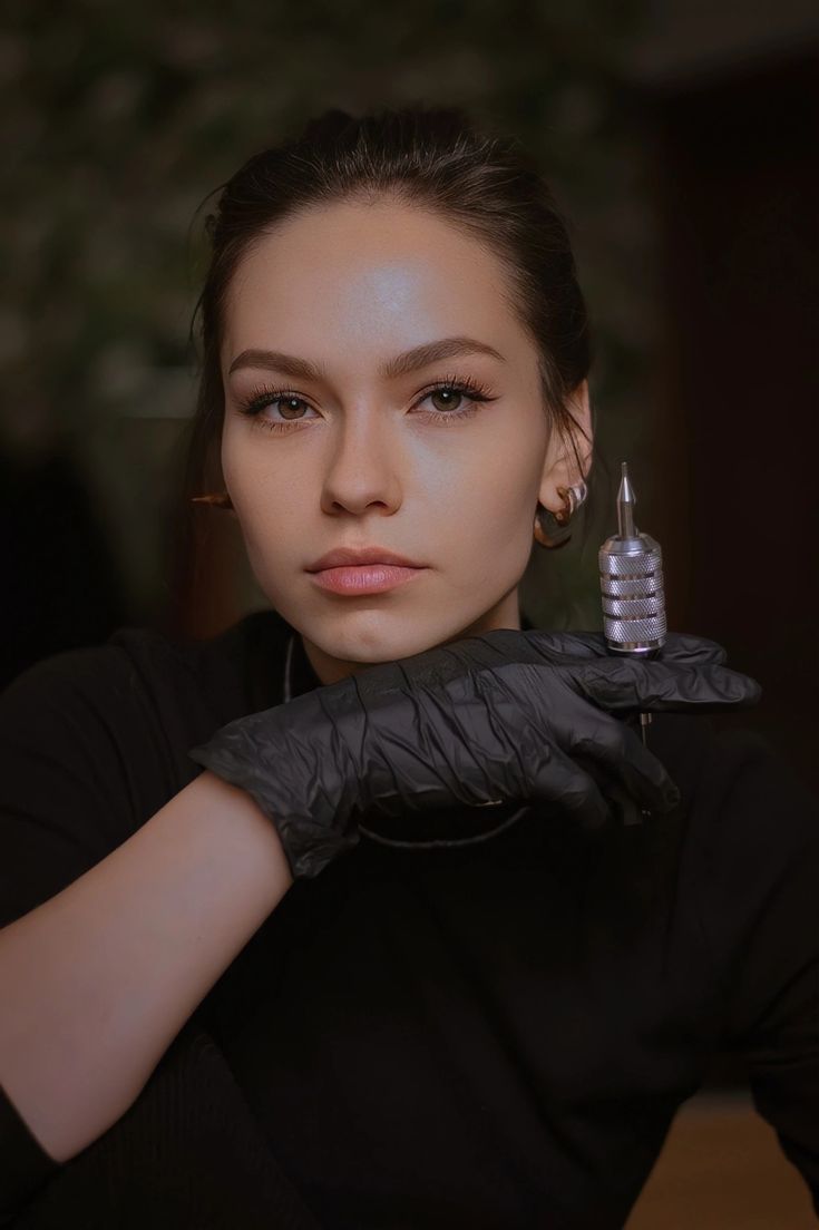 a woman wearing black gloves and holding a small object in her right hand while looking at the camera