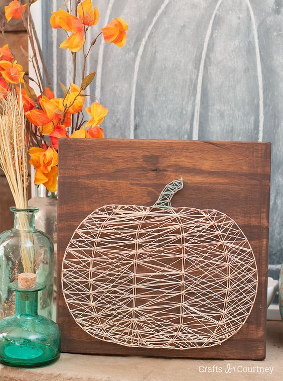 a wire pumpkin sitting on top of a wooden board next to vases with flowers