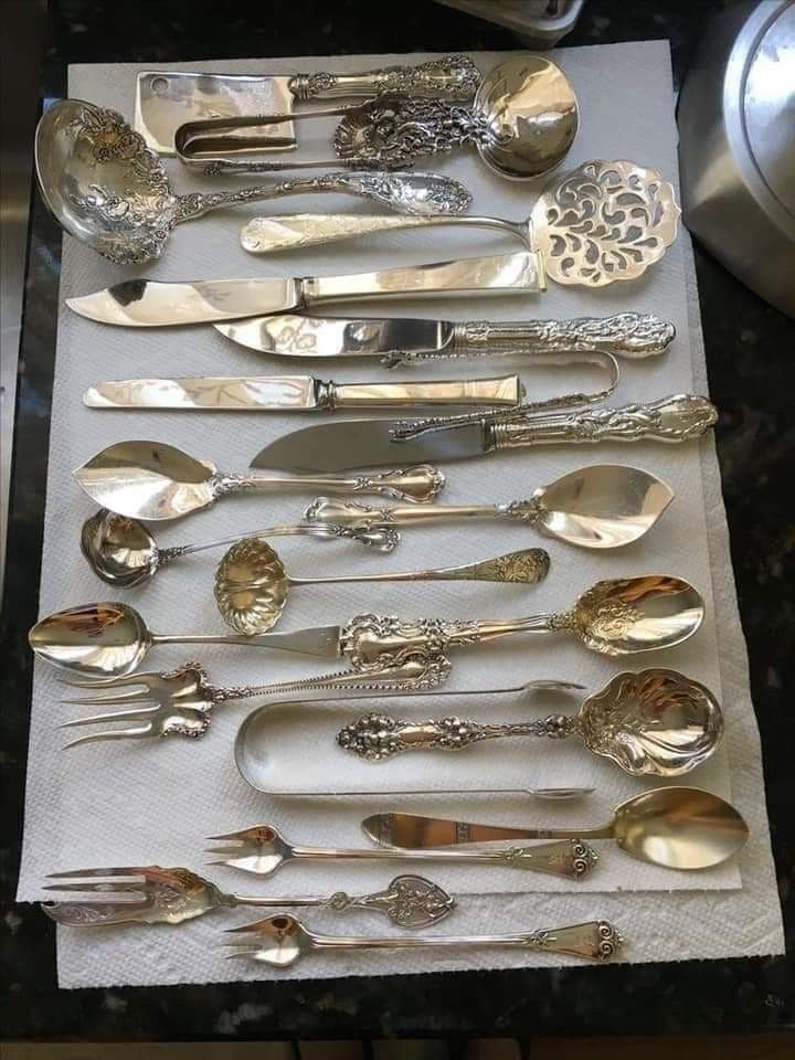 silverware is laid out on a white cloth with spoons and knives in it