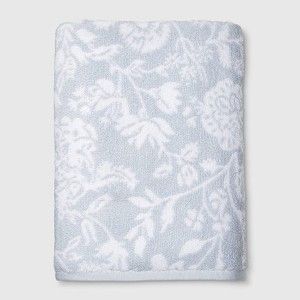 the blue and white floral towel is folded on top of a white tablecloth with an embroidered design