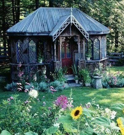 a small wooden building surrounded by flowers and trees