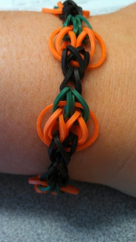 an orange, black and green bracelet on someone's arm that is made out of rubber bands