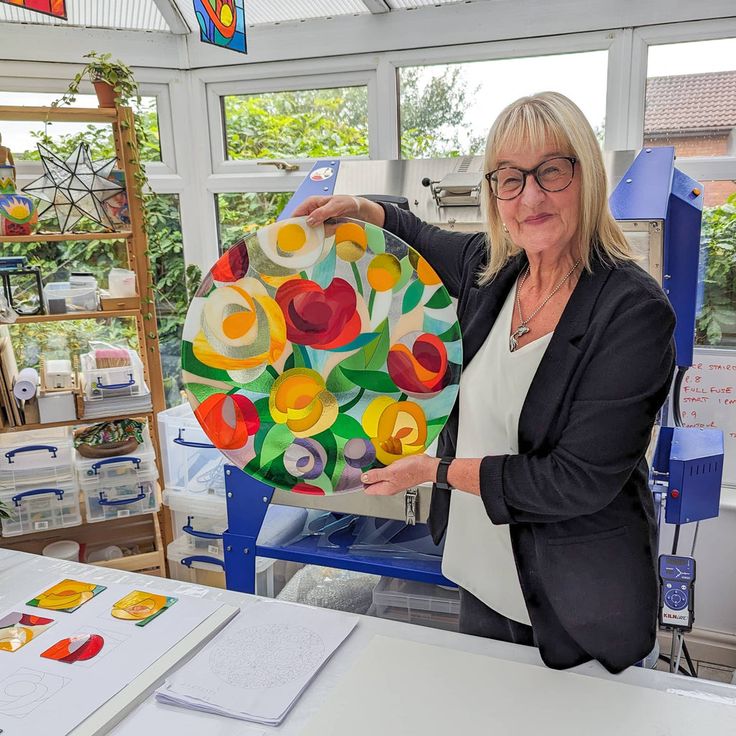 a woman holding up a colorful piece of art