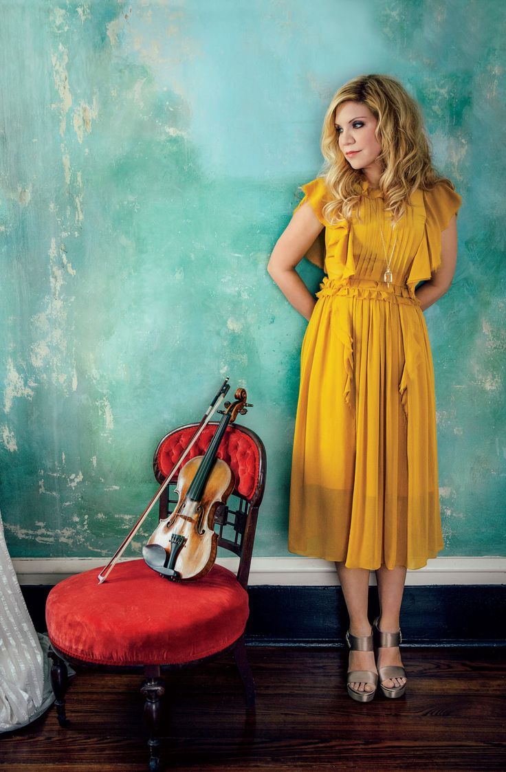 a woman standing next to a chair with a violin on it