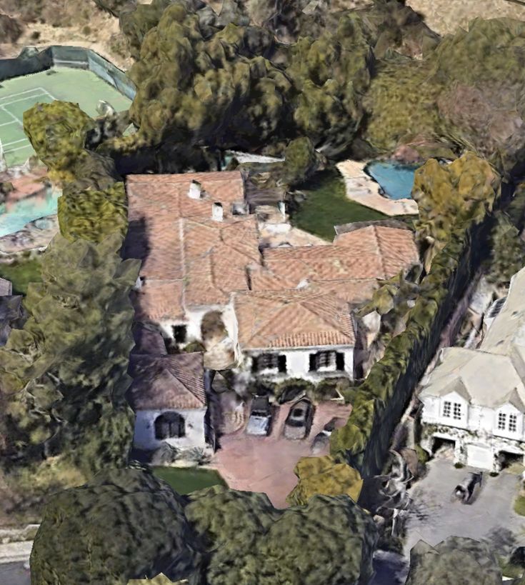 an aerial view of a large house with many trees around it and a tennis court on the other side