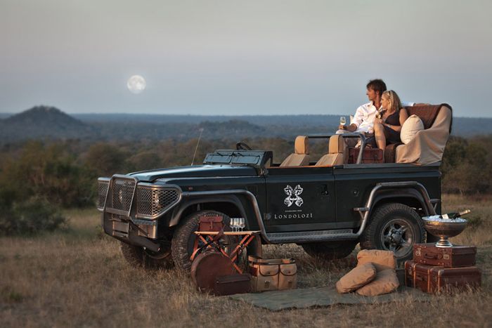 a black jeep parked on top of a grass covered field next to a pile of luggage