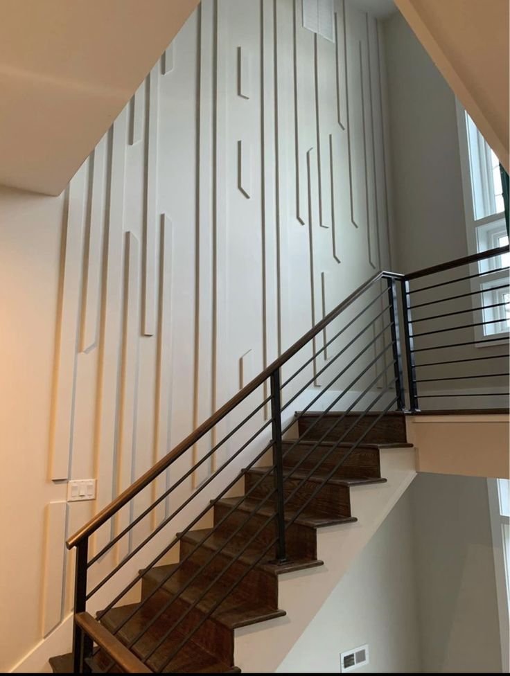 a stair case with metal handrails next to a white wall and wooden steps